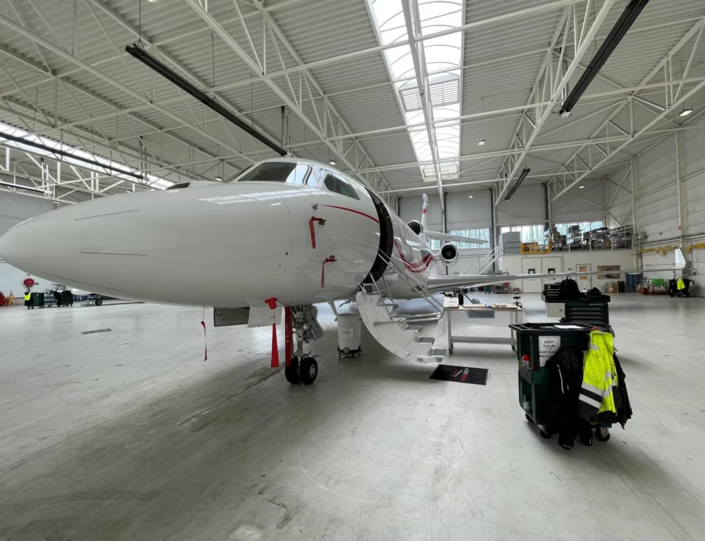 Private jet in a FLYINGGROUP maintenance hangar with ground equipment